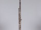 a silver flute on a clear stand against a gray background