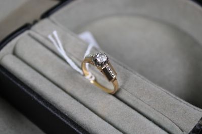 a diamond ring in a ring box with a ribbon around it