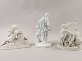 three figurines of a man and a woman sitting on a bench