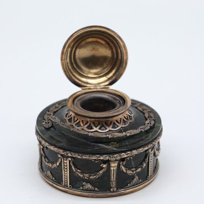 a small black box with a gold lid on a white surface