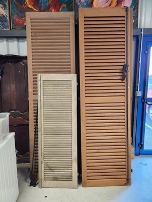 deux volets en bois dans une pièce, avec un tableau accroché au mur derrière eux