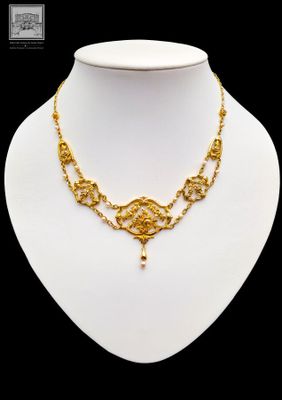 a close up of a gold necklace on a mannequin