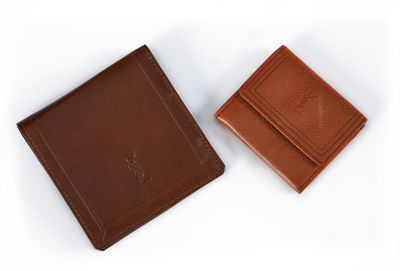 deux portefeuilles en cuir marron posés l'un à côté de l'autre sur une surface blanche