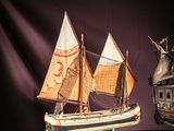 two models of a ship on display on a purple surface