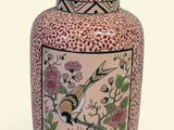 un vase rose orné d'un oiseau et de fleurs