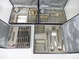 des couverts dans un coffret en argent posé sur une table blanche