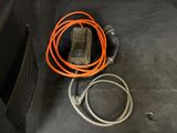 an orange cord connected to a cell phone in the trunk of a car