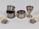 une coupe en argent et d'autres objets en argent posés sur une surface blanche