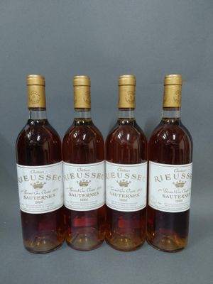 quatre bouteilles de vin sont alignées sur une surface grise