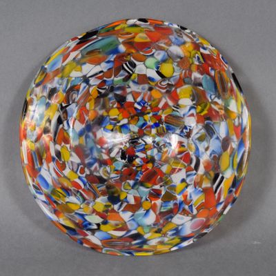 un bol multicolore posé sur une table, sur fond gris