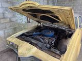 an old yellow car with the hood open and the engine in the trunk