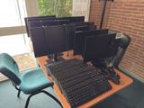 many computer monitors and keyboards on a desk in a room