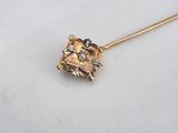 a close up of a gold and diamond broochle on a white surface