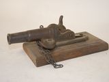 an old gun on a wooden block with a chain