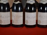 four bottles of wine are lined up on a red table