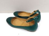 pair of women ' s green leather shoes with bows on the toes