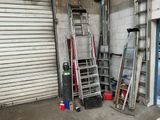 de nombreuses échelles dans un garage, appuyées contre le mur