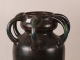 a black vase with a green handle sitting on a table