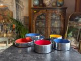 four metal bowls sitting on top of a table in a room