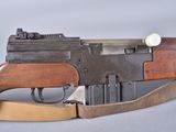 an old machine gun with a wooden handle on a gray surface