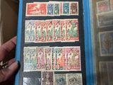 Quelqu'un tient un livre sur lequel sont collés plusieurs timbres.