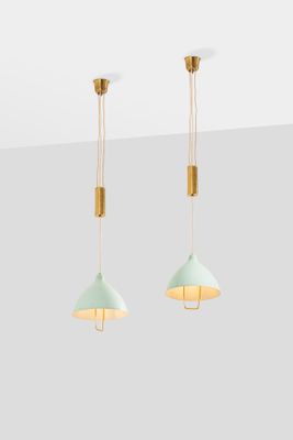 a pair of light green and gold pendant lights hanging from a ceiling