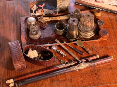 a wooden table topped with a tray filled with antique items