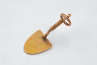 a small metal object with a wooden handle on a white surface