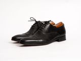 un gros plan sur une paire de chaussures noires posées sur une surface blanche