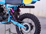 a blue dirt bike parked on a stand in a parking lot
