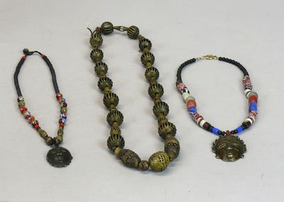 Trois colliers, l’un de perles de laiton ajouré, les deux au…