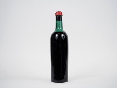 une bouteille noire avec un bouchon rouge posée sur une surface blanche