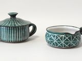 deux théières et une tasse posées sur un plan de travail blanc