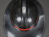 a black fireman ' s hat hanging on a wall