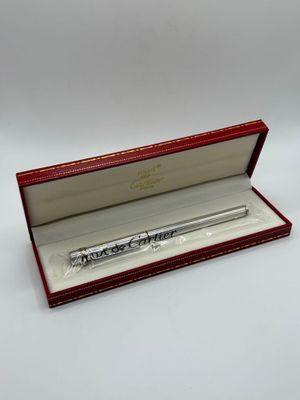 un gros plan d'un stylo dans une boîte rouge posée sur une surface blanche