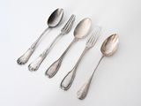 five silver spoons and two silver spoons on a white surface