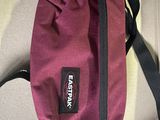 purple and black bag with a tag attached to it sitting on a table