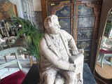 a statue of a man sitting on a chair in a living room