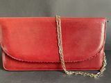 a red leather clutch bag with a gold chain strap