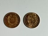 two gold coins sitting side by side on a white surface
