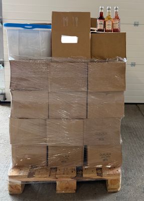 une grande pile de cartons posée sur une palette devant la porte d'un garage