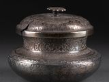 un vieux vase en argent muni d'un couvercle, sur fond noir