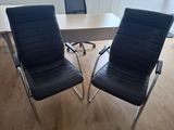 une paire de fauteuils de bureau en cuir noir placés devant une table en bois