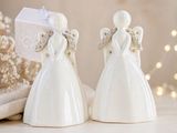 two figurines of angels on a table with a gift