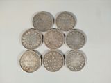 six different british coins sitting on top of each other on a white surface