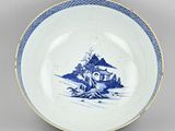 a blue and white plate with a picture of a man sitting on a rock