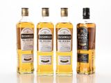 four bottles of whisky are lined up on a white surface