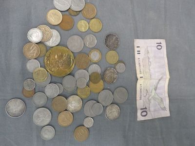 un tas de pièces et un billet posés sur une table