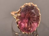 pink tourmaline ring with gold accents on a clear surface