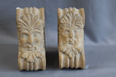 pair of carved stone bookends of a man and a woman ' s face